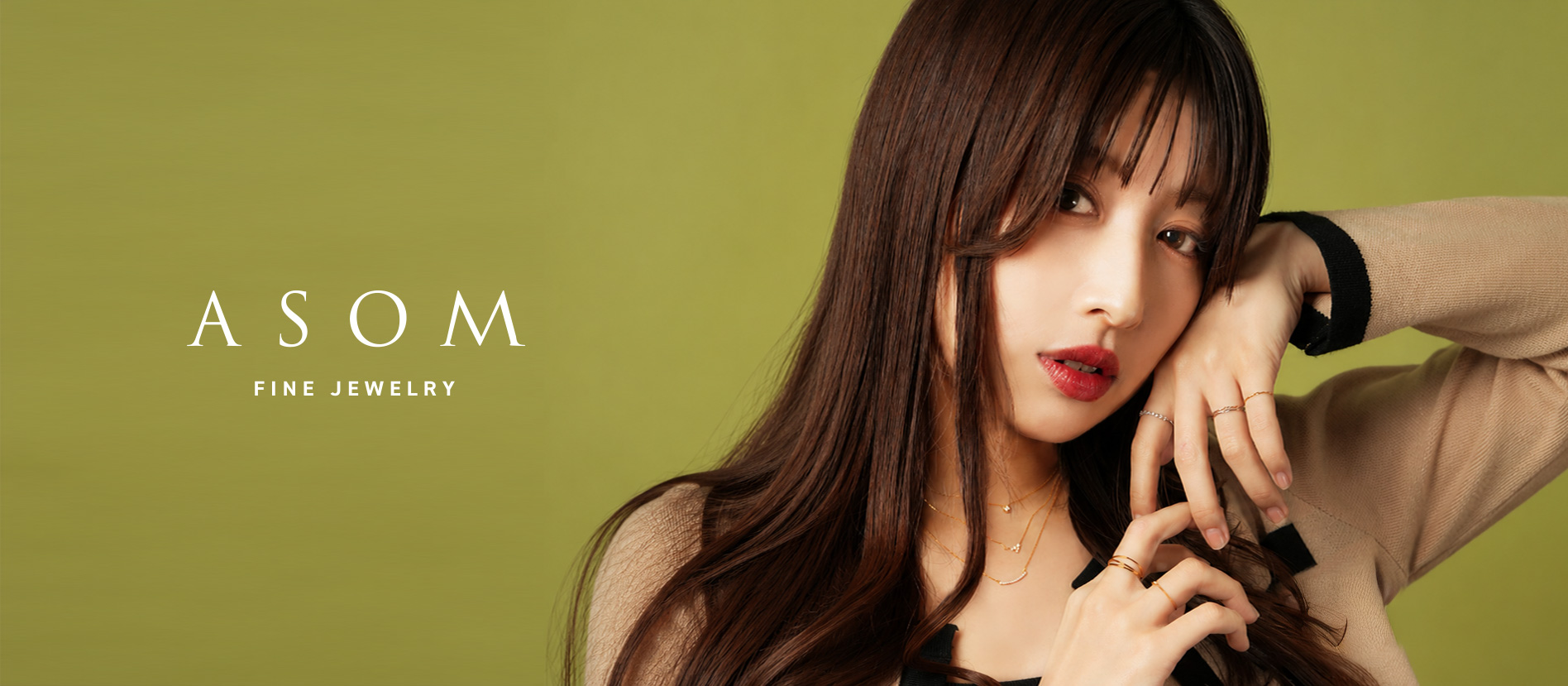 ASOM FINE JEWELRY ── ベージュのニットに、ゴールドのネックレスとリングを重ねづけした女性