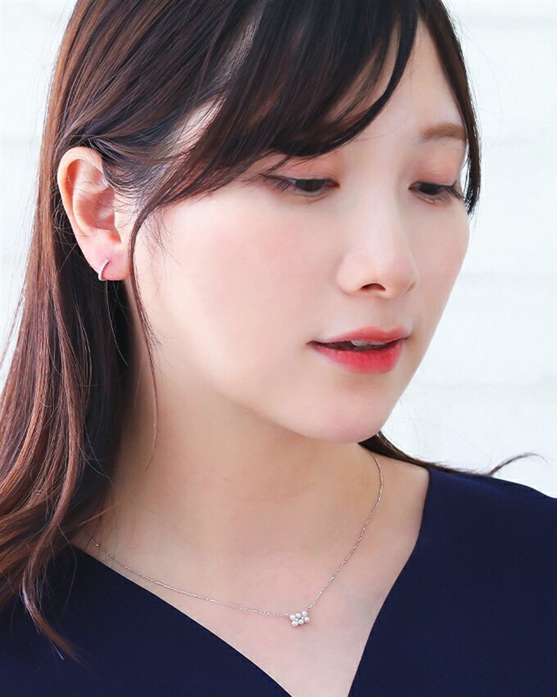 ネイビーのトップスに、ホワイトゴールドのパールのペンダントを合わせた女性
