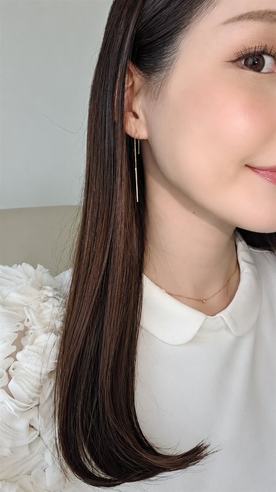 白い丸襟のブラウスに、耳元で揺れる細いバーのチェーンピアスと華奢なネックレス